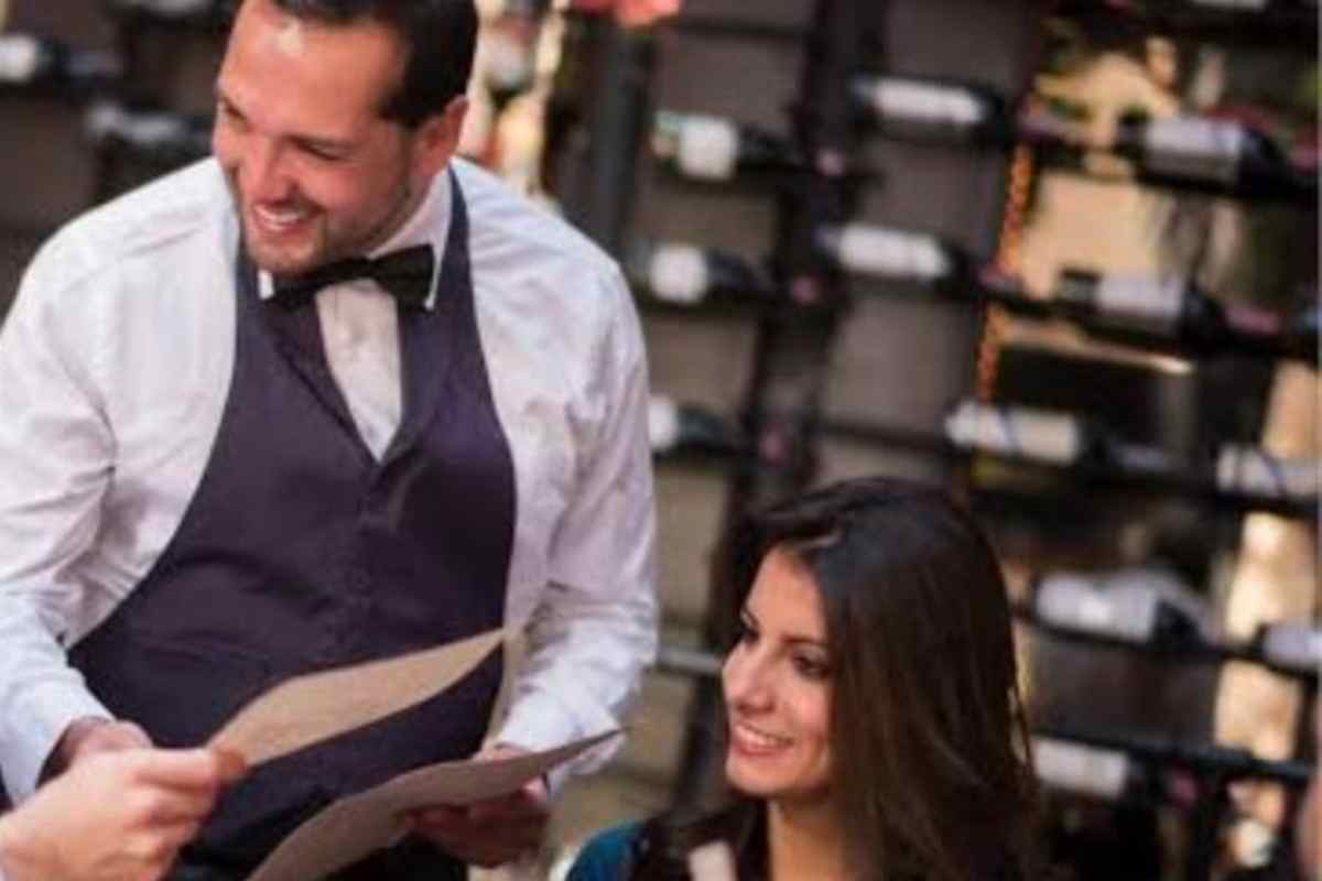 un cameriere di sala sorride ai clienti